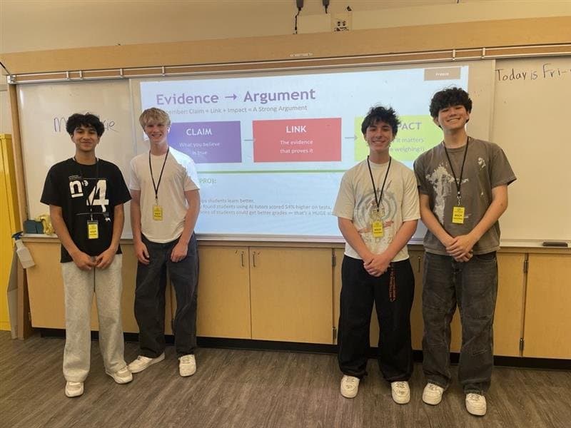 Four Uplift Debate volunteers standing in front of a presentation slide reading 'Evidence to Argument.'